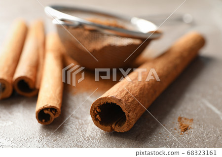 Cinnamon sticks, powder and sieve on grey Cinnamon sticks, powder and sieve on grey 68323161