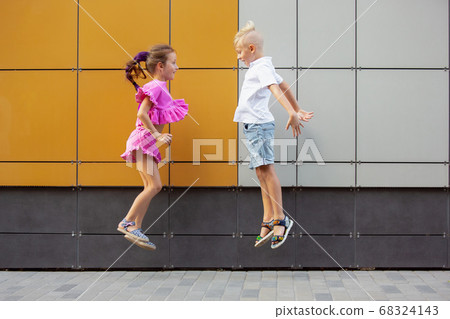 Two smiling kids, boy and girl running together in town, city in summer day Two smiling kids, boy and girl running together in town, city in summer day 68324143