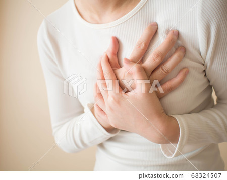 Heart attack/problems. Young female suffering from severe chest pain. Warning signs of unstable angina or myocardrial infarction disease. Health care and cardiological concept. Close up. Heart attack/problems. Young female suffering from severe chest pain. Warning signs of unstable angina or myocardrial infarction disease. Health care and cardiological concept. Close up. 68324507