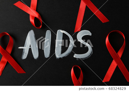 Red awareness ribbon and inscription AIDS on black 68324829