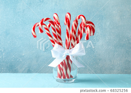 Candy canes in glass jar on blue background, space Candy canes in glass jar on blue background, space 68325256