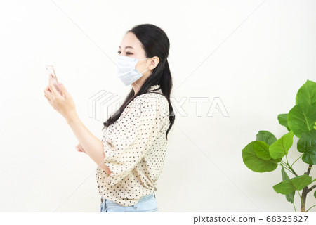 Woman with smartphone wearing mask Woman with smartphone wearing mask 68325827