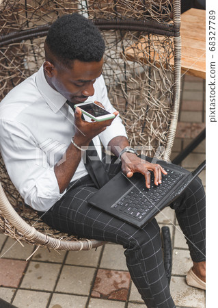 Business african american man holding smartphone, dictating voice message, recording audio, using voice mic. People works outdoors 68327789
