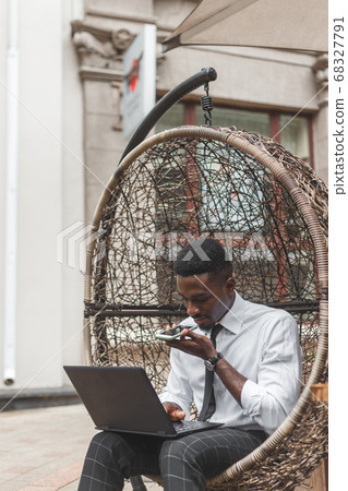 Business african american man holding smartphone, dictating voice message, recording audio, using voice mic. People works outdoors 68327791