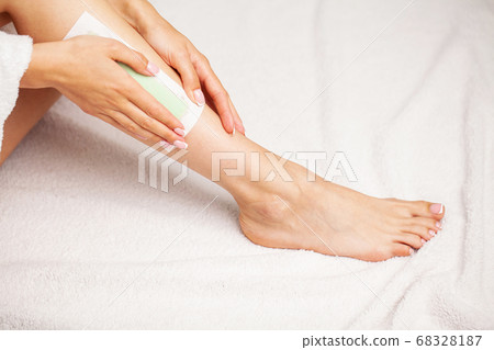 Waxing woman leg with wax strip at beauty spa 68328187