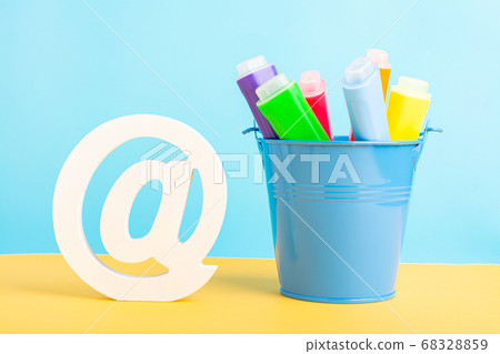 A metal bucket with highlighter marker pen and at symbol or commercial at on a blue background. Back to school 68328859