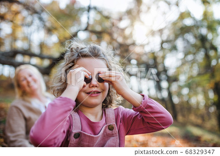 Small girl with grandmother on a walk in autumn forest, having fun. Small girl with grandmother on a walk in autumn forest, having fun. 68329347