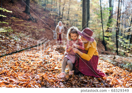 Small girl with mother and grandmother on a walk in autumn forest. Small girl with mother and grandmother on a walk in autumn forest. 68329349