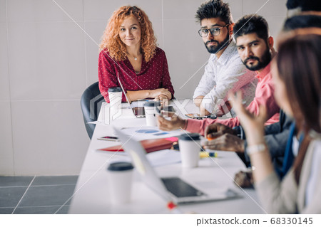 Mixed race people listening to presentation sitting in row at boardroom table 68330145