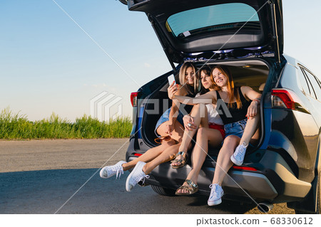 Three happy female friends at car trunk Three happy female friends at car trunk 68330612