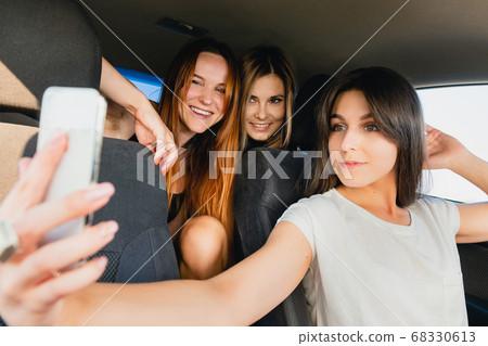 Three girls make selfie at car salon 68330613