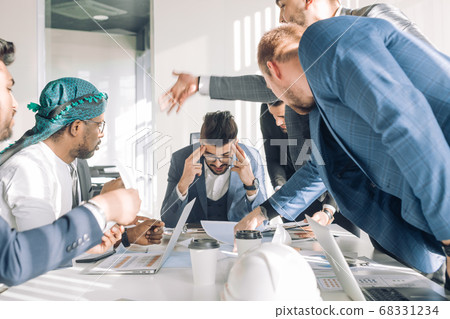Young boss with colleagues looking at him during meeting at conference room 68331234