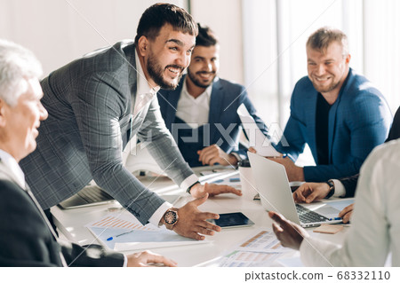Corporate interracial business team with cheerful leader in a meeting, close up Corporate interracial business team with cheerful leader in a meeting, close up 68332110