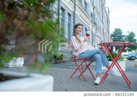 Smiling female sitting with crossed legs, enjoying red wine in cafe 68332189