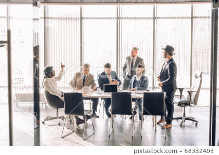 Serious Indian CEO in interacting with multiracial vendors at corporate meeting 68332403