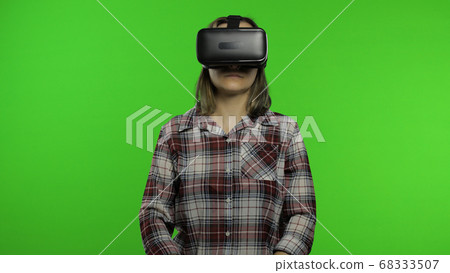 Young woman using VR headset helmet to play game. Watching virtual reality 3d 360 video. Chroma key Young woman using VR headset helmet to play game. Watching virtual reality 3d 360 video. Chroma key 68333507