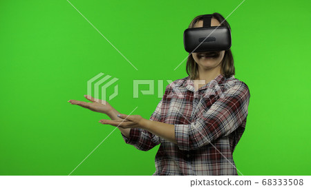 Young woman using VR headset helmet to play game, showing side advertising area. Chroma key 68333508