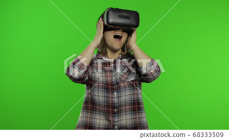 Girl using VR app helmet to play simulation scary game. Woman watching virtual reality 3D video Girl using VR app helmet to play simulation scary game. Woman watching virtual reality 3D video 68333509
