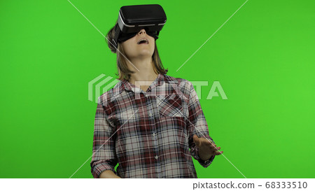 Young woman using VR headset helmet to play game. Watching virtual reality 3d 360 video. Chroma key Young woman using VR headset helmet to play game. Watching virtual reality 3d 360 video. Chroma key 68333510