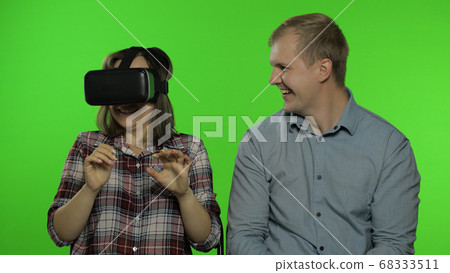 Man and woman using VR headset helmet to play game. Watching virtual reality 3D video. Chroma key Man and woman using VR headset helmet to play game. Watching virtual reality 3D video. Chroma key 68333511