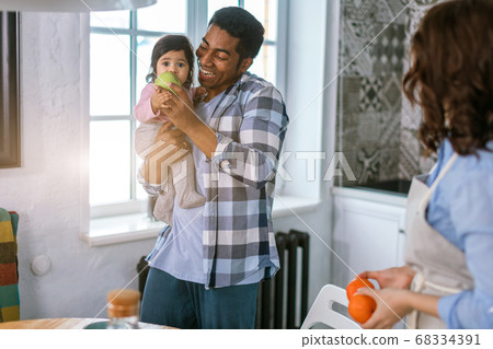 little girl eathing fruit while being hold in her daddy's arms little girl eathing fruit while being hold in her daddy's arms 68334391