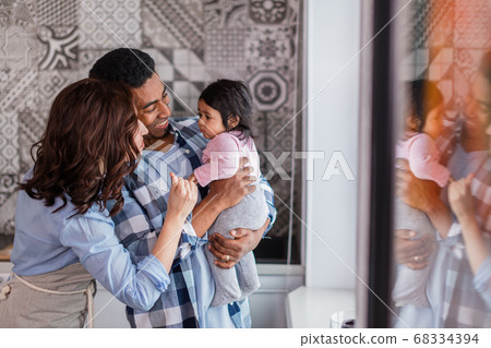 young cheerful mixed raced parents take care of their kid 68334394