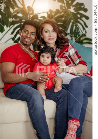 Happy parents and baby girl sitting on the couth and posing to the camera 68334410