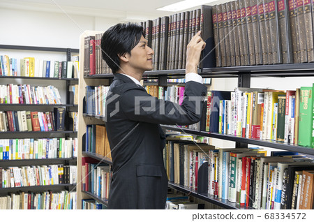 Young men looking for books in the library Young men looking for books in the library 68334572