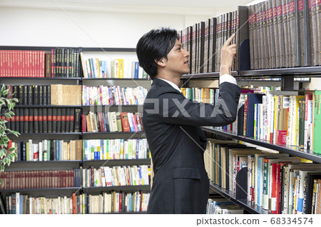 Young men looking for books in the library Young men looking for books in the library 68334574