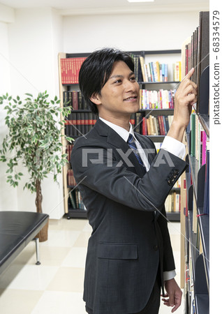 年輕人在圖書館裡找書 年輕人在圖書館裡找書 68334579