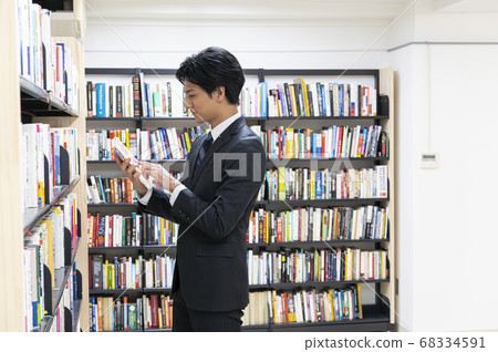 Young men reading books in the library Young men reading books in the library 68334591