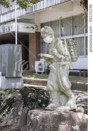 A stone statue of Kinjiro Ninomiya wearing a mask 68335246