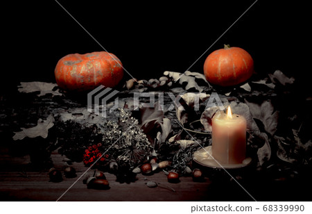 Altar of a forest witch in the dark. Pumpkins, candle, nuts, dry black leaves, selected focus, low key 68339990