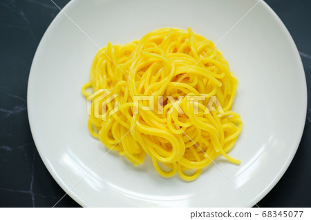 The noodles are in a round white plate placed on table.yellow noodle.top view food. The noodles are in a round white plate placed on table.yellow noodle.top view food. 68345077