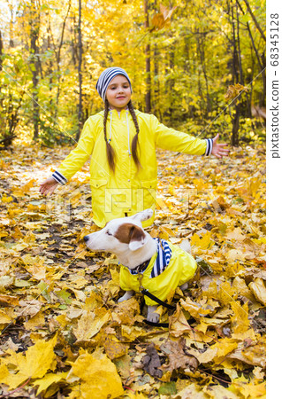 Little girl playing with her dog in autumn forest. Child and jack russell terrier dog. 68345128