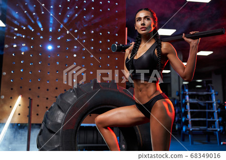 Female bodybuilder posing with sledgehammer on shoulders. 68349016