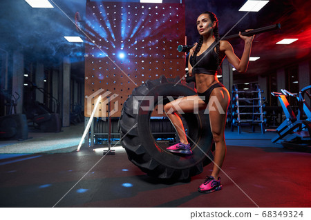 Muscular woman posing with sledgehammer on shoulders. Muscular woman posing with sledgehammer on shoulders. 68349324