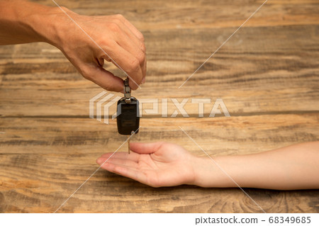 Human hands holding car key isolated on wooden background with copyspace Human hands holding car key isolated on wooden background with copyspace 68349685
