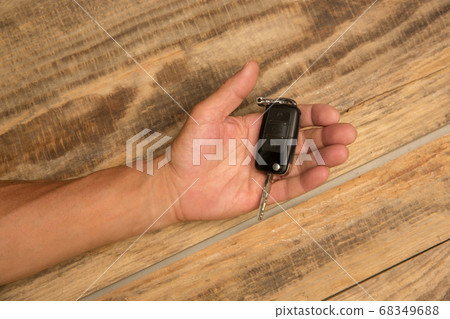 Human hands holding car key isolated on wooden background with copyspace 68349688