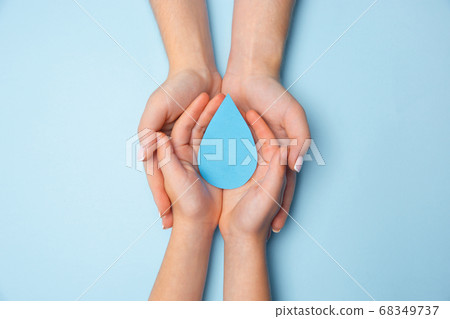 Human hands holding water drop isolated on white wooden background 68349737