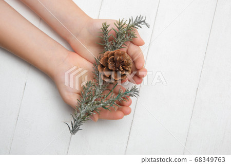 Human's hand holding a Christmas decoration isolated on white wooden background Human's hand holding a Christmas decoration isolated on white wooden background 68349763