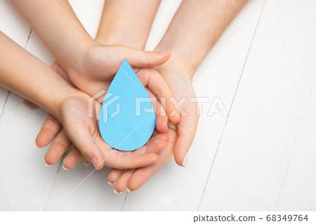 Human hands holding water drop isolated on white wooden background Human hands holding water drop isolated on white wooden background 68349764