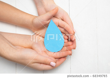 Human hands holding water drop isolated on white wooden background 68349765