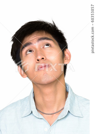 Studio shot of young Asian man thinking and looking up isolated against white background Studio shot of young Asian man thinking and looking up isolated against white background 68353857