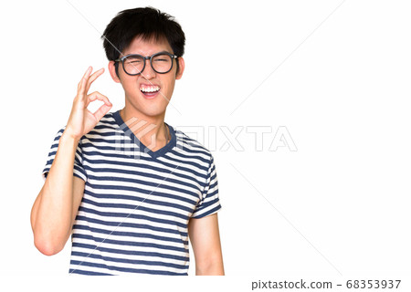 Studio shot of happy Asian nerd guy winking and making OK sign isolated against white background 68353937