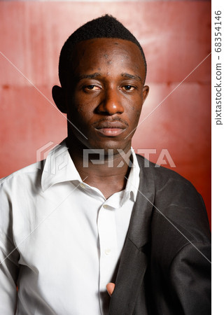 Young African businessman against red metal wall Young African businessman against red metal wall 68354146