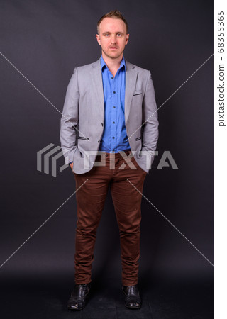 Handsome businessman with blonde hair against black background 68355365