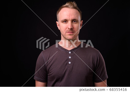 Handsome man with blonde hair against black background Handsome man with blonde hair against black background 68355416