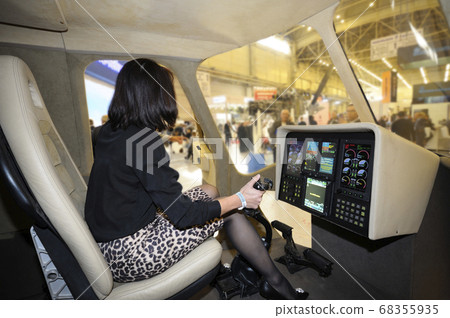 Woman sitting in a cockpit of a passenger helicopter in pilots seat in front of dashboard Woman sitting in a cockpit of a passenger helicopter in pilots seat in front of dashboard 68355935