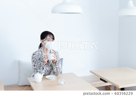 Woman wearing a mask and drinking tea Woman wearing a mask and drinking tea 68356229